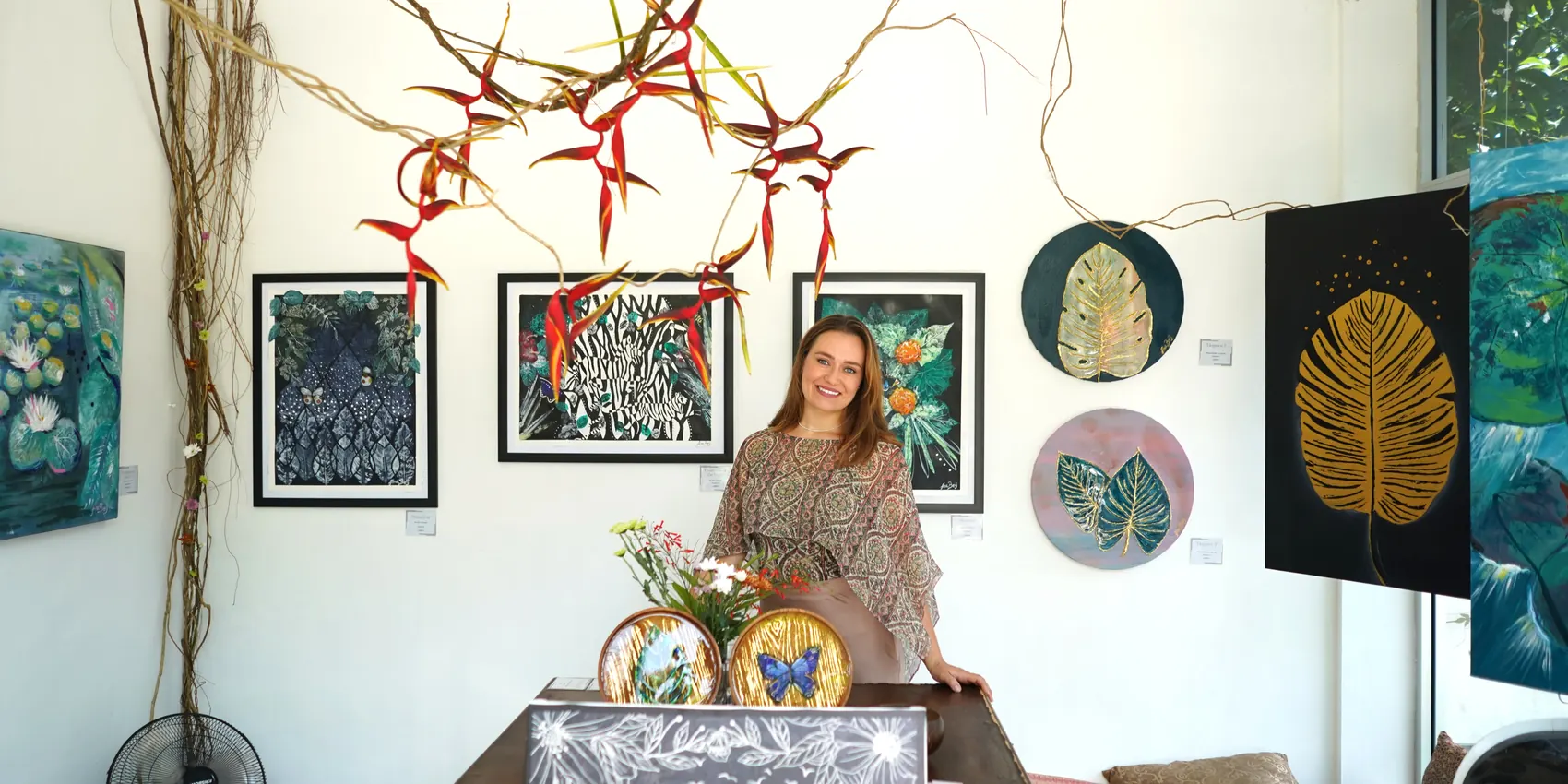 Ana in a gallery room hung with her botanical artworks